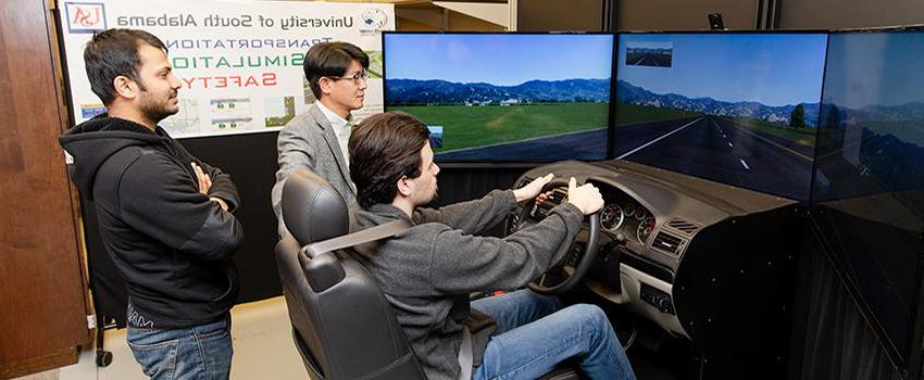 Civil Engineering students using the driving simulator with professor.
