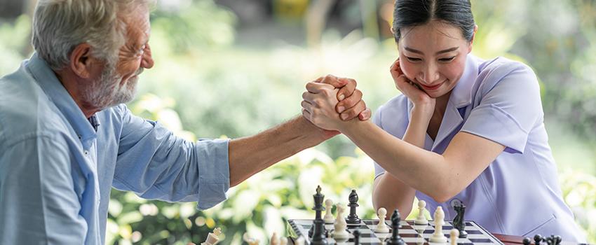 老年男子和年轻女子在象棋比赛后握手.
